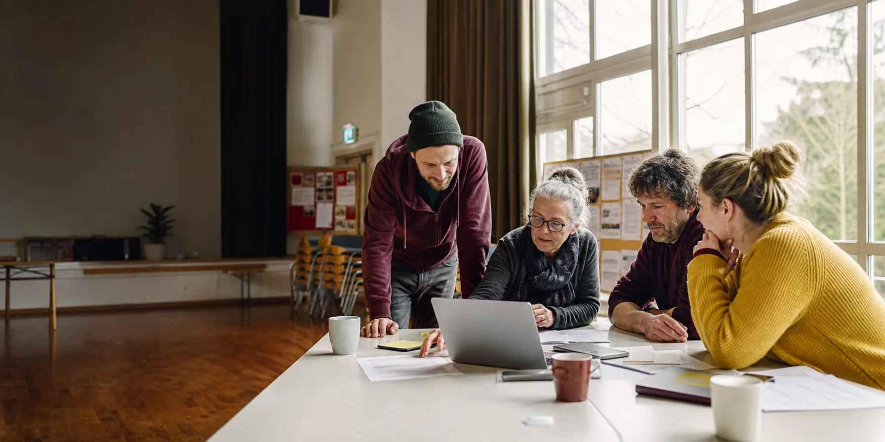 Ehrenamtliche aus verschiedenen Generationen planen gemeinsam an einem Laptop